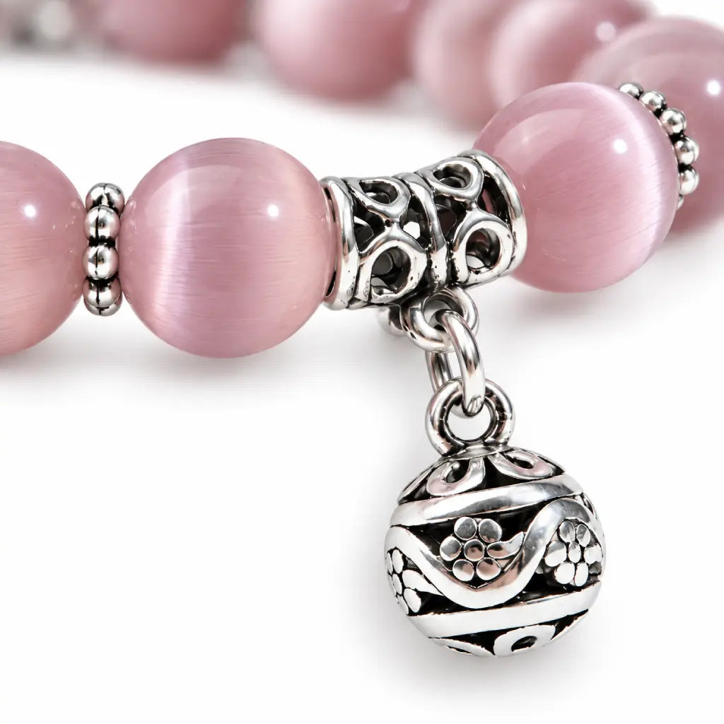Pink Catseye bracelet featuring luminous pink cat eye beads, silver spacers and an ornate charm for polished elegance.