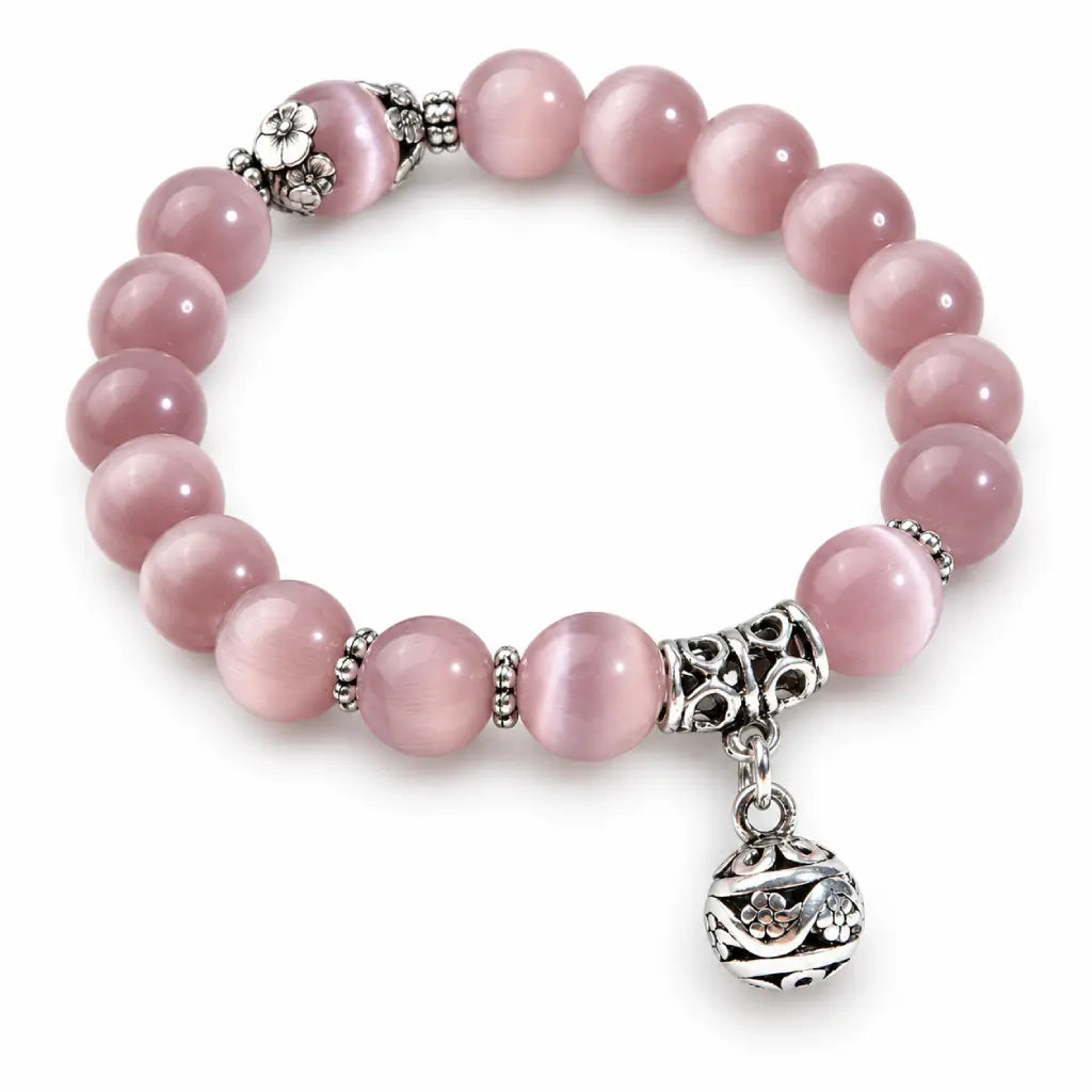Pink Catseye bracelet close-up showing a luminous pink bead with ornate silver floral accents and polished detailing.