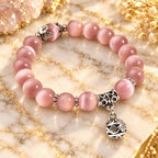 Pink Catseye bracelet featuring luminous pink cat eye beads and an ornate silver charm, styled for elegant everyday wear.