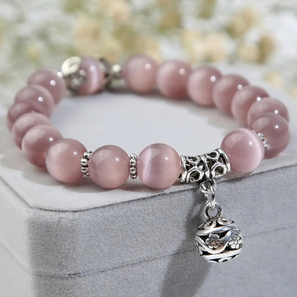 Pink Catseye bracelet displayed on a jewelry box with luminous pink beads and silver charm, ideal for elegant gifting.