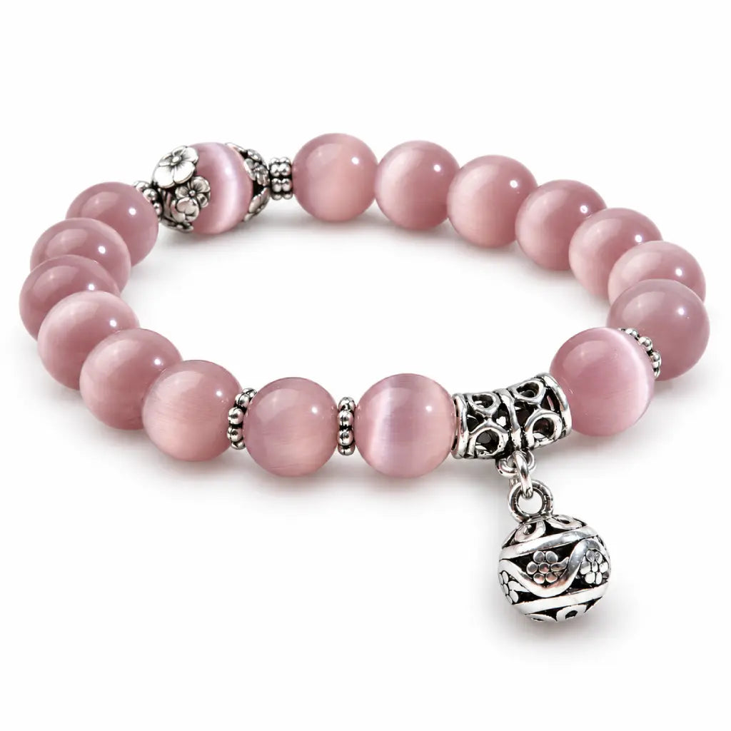 Pink Catseye bracelet with glossy round pink beads, floral silver accents and a decorative charm for feminine styling.