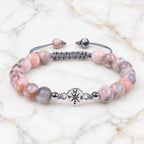 Pink Zebra Jasper bracelet with polished gemstone beads and silver charm on marble background for elegant healing style