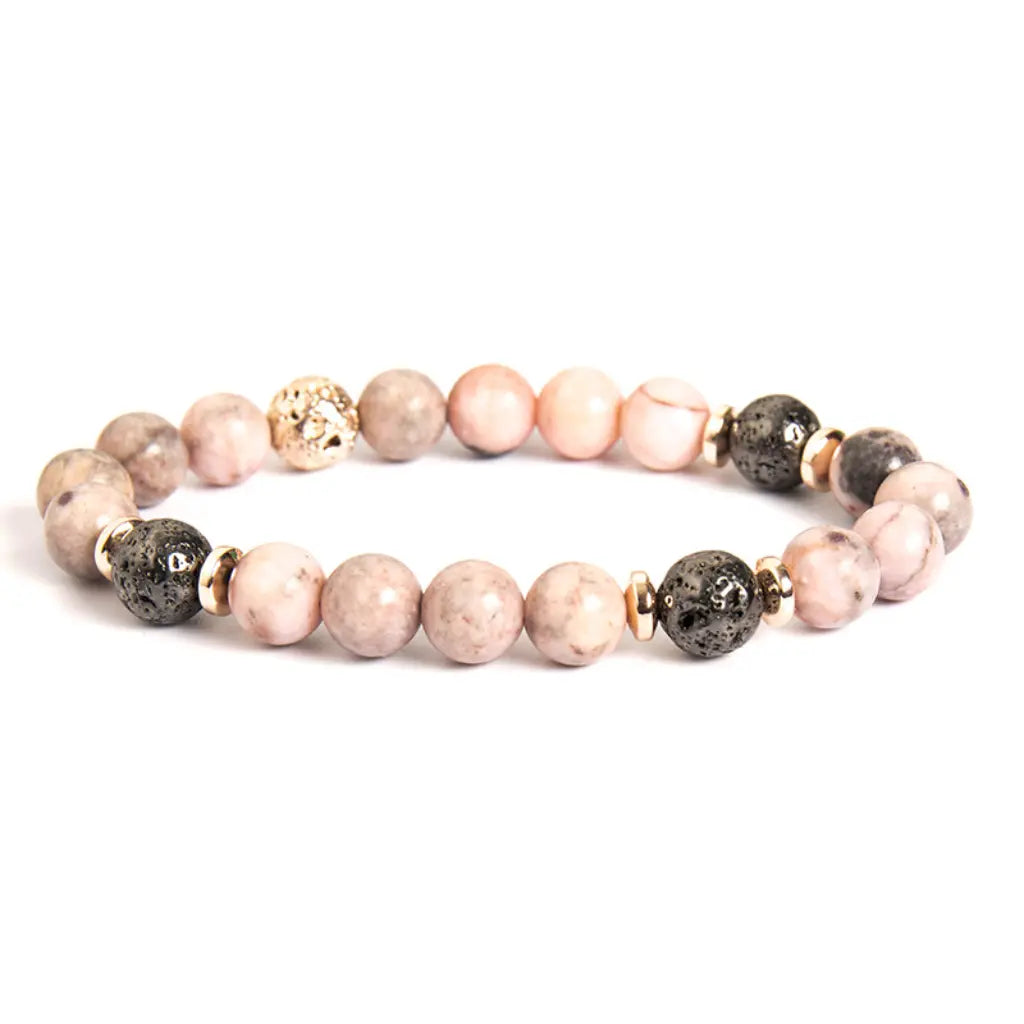 pink zebra jasper bracelet with black lava beads and gold accents on white background for elegant wellness style