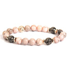 pink zebra jasper bracelet with black lava beads and gold accents on white background for elegant wellness style