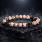 pink zebra jasper luxury bracelet with black lava beads and gold accents on dark stone for elegant wellness