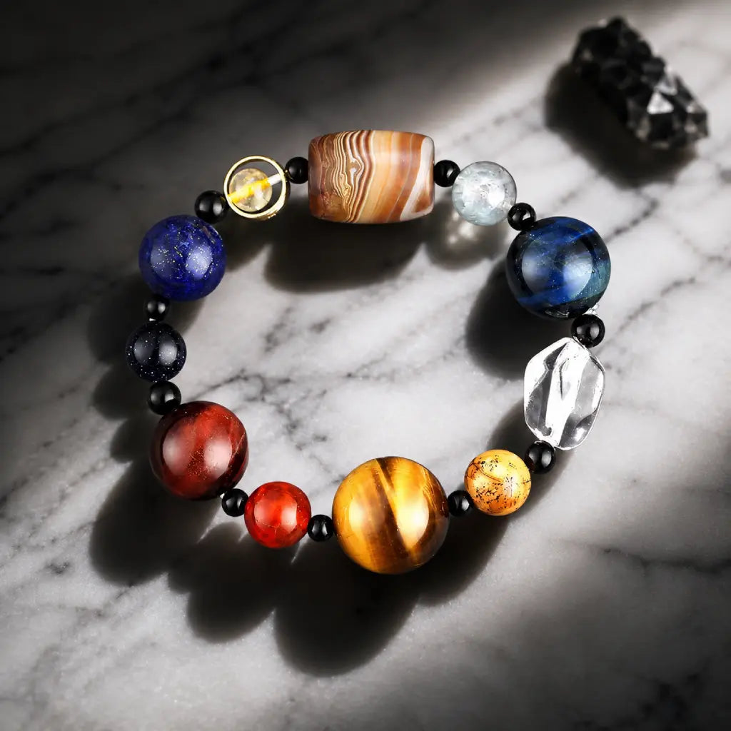 Planet bead tiger eye gemstone bracelet photographed with dramatic lighting, emphasizing polished natural stones, quartz, and tiger eye brilliance.