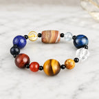 Planet bead tiger eye gemstone bracelet displayed at an elegant angle with natural tiger eye, quartz, agate, and colorful gemstone beads on marble.