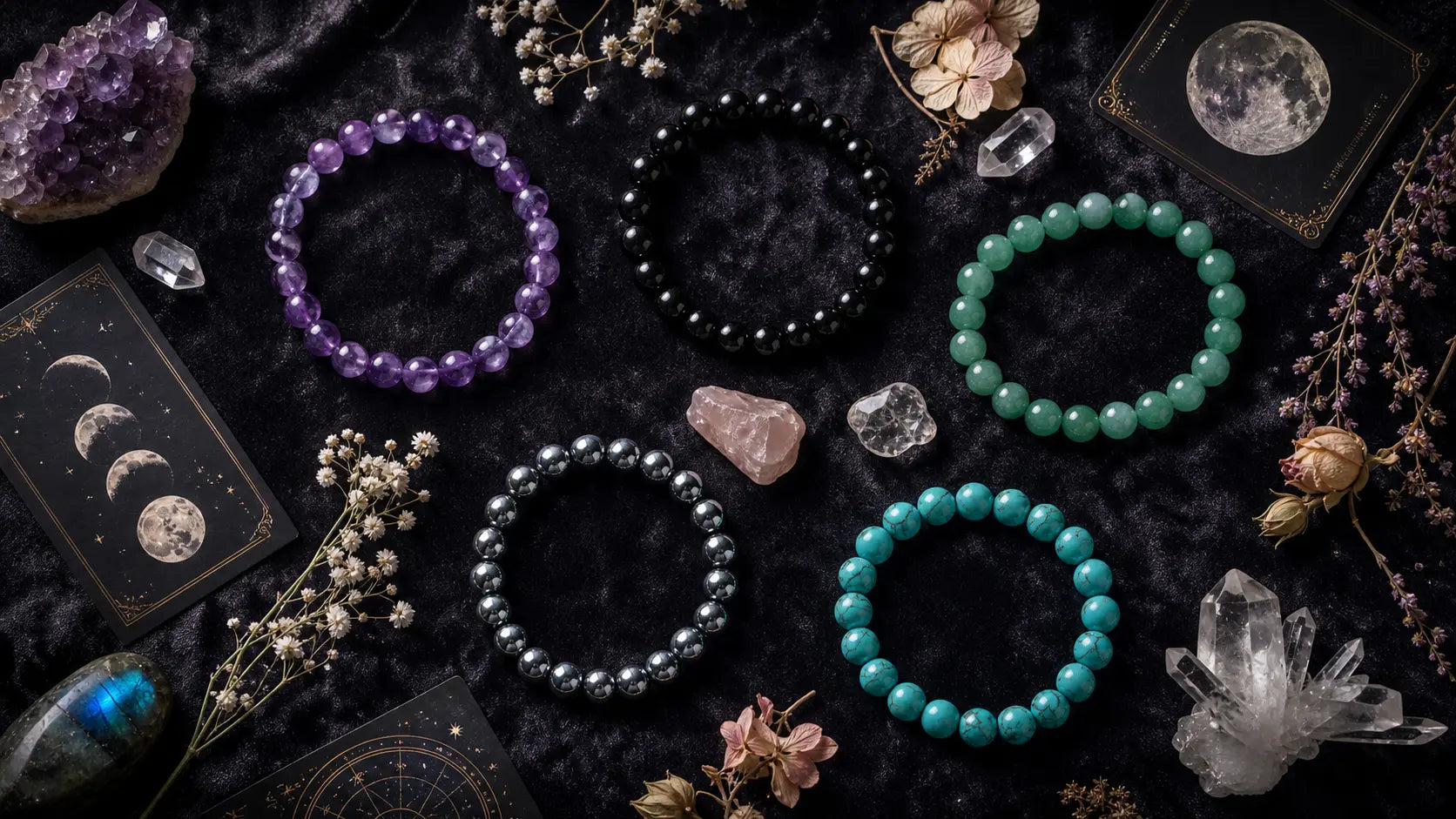 Four beaded bracelets in purple, black, and green on a dark surface with crystals and tarot cards.