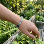 Rainbow Fluorite Crystal Bracelet worn outdoors in garden, green purple tones blending with nature for calming grounding energy feel
