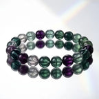 Rainbow Fluorite Crystal Bracelet on white reflective surface, clean product shot highlighting bead clarity and premium polished finish