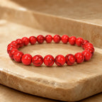 Red howlite bracelet with polished gemstone beads on a natural stone display for stylish healing energy wear
