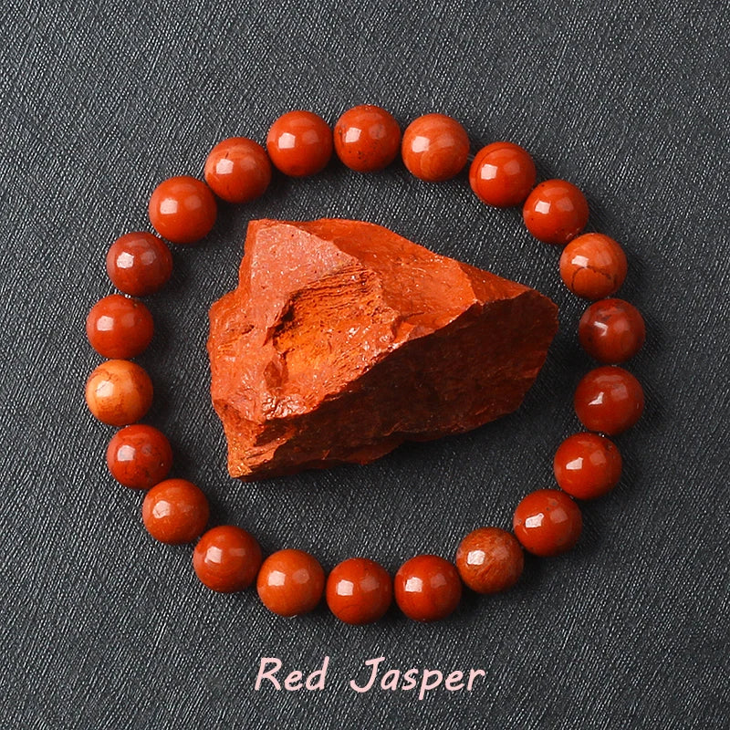 Red Jasper bracelet with deep brick-red polished beads surrounding a raw Red Jasper specimen on dark background