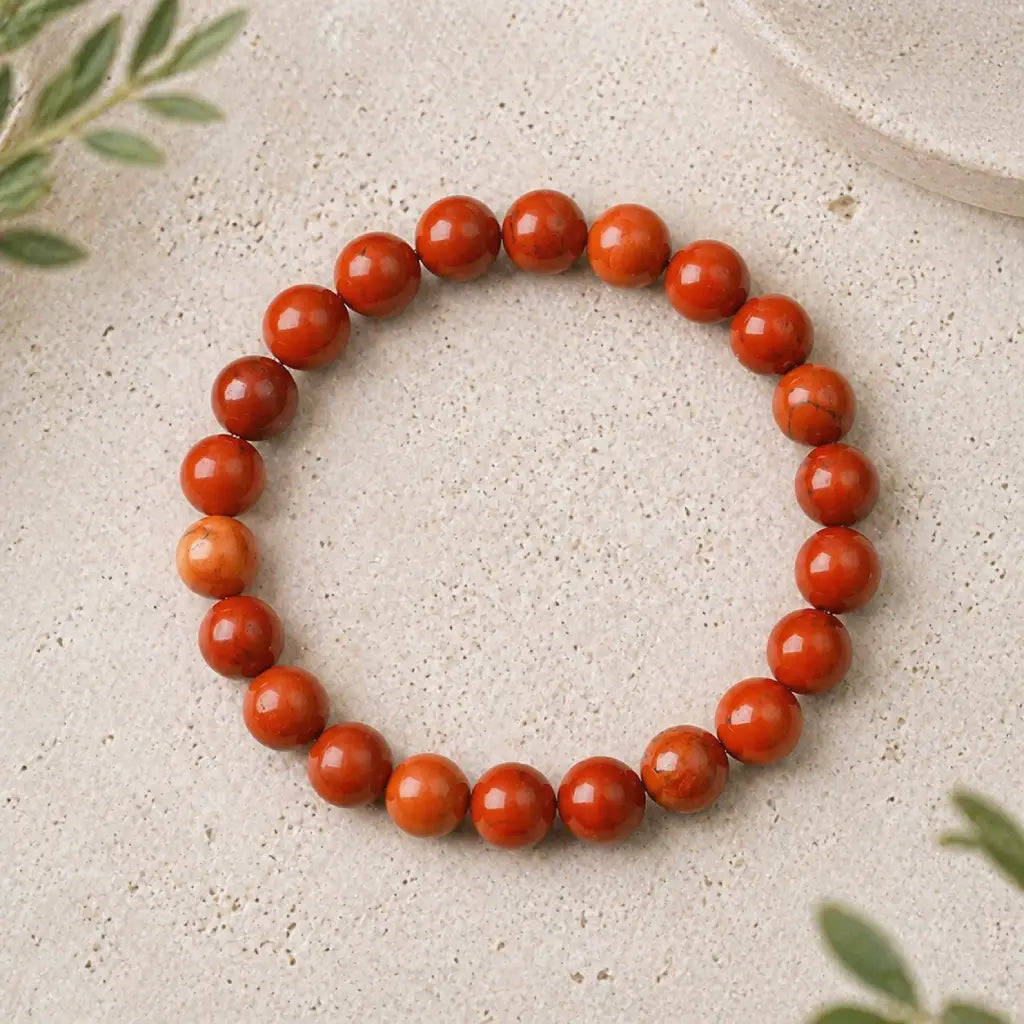 Red jasper stone bracelet glossy red bead stretch bracelet on stone surface, energizing crystal jewelry daily wear