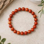 Red jasper stone bracelet glossy red round bead bracelet on travertine with driftwood, bold grounding jewelry look