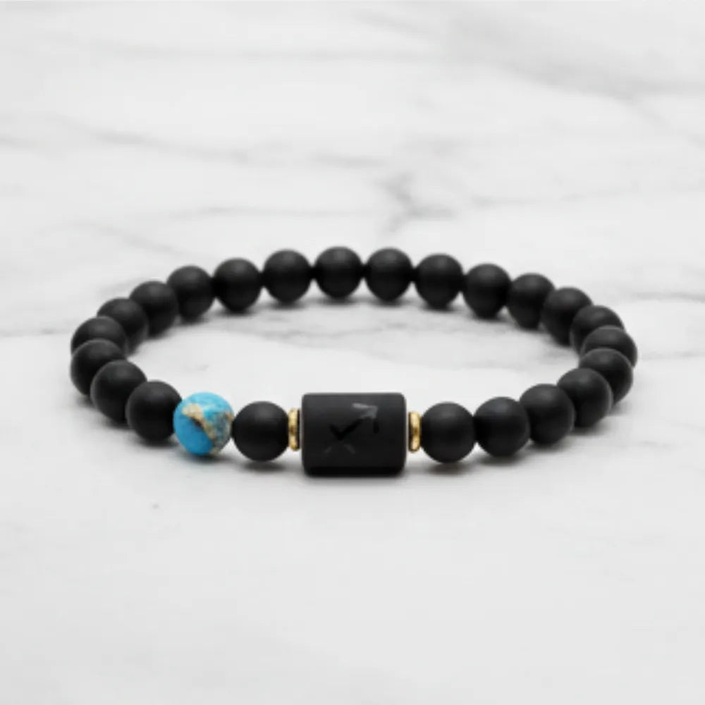 Sagittarius zodiac bracelet close-up on wooden surface highlighting matte black beads and engraved center charm