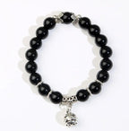 A beaded stretch bracelet featuring glossy black round beads, silver-toned spacer beads, and a dangling silver bell charm, displayed on a clean white background.