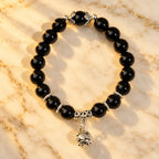 Shadow guardian obsidian bracelet featuring polished black beads, silver spacers and a dangling charm for refined everyday style.
