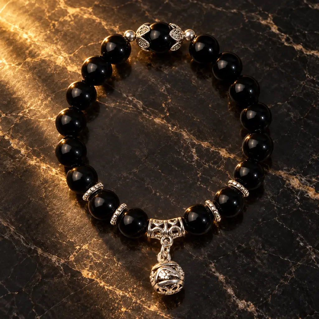 Shadow guardian obsidian bracelet with glossy black beads and detailed silver accents, styled on dark marble for a luxe look.