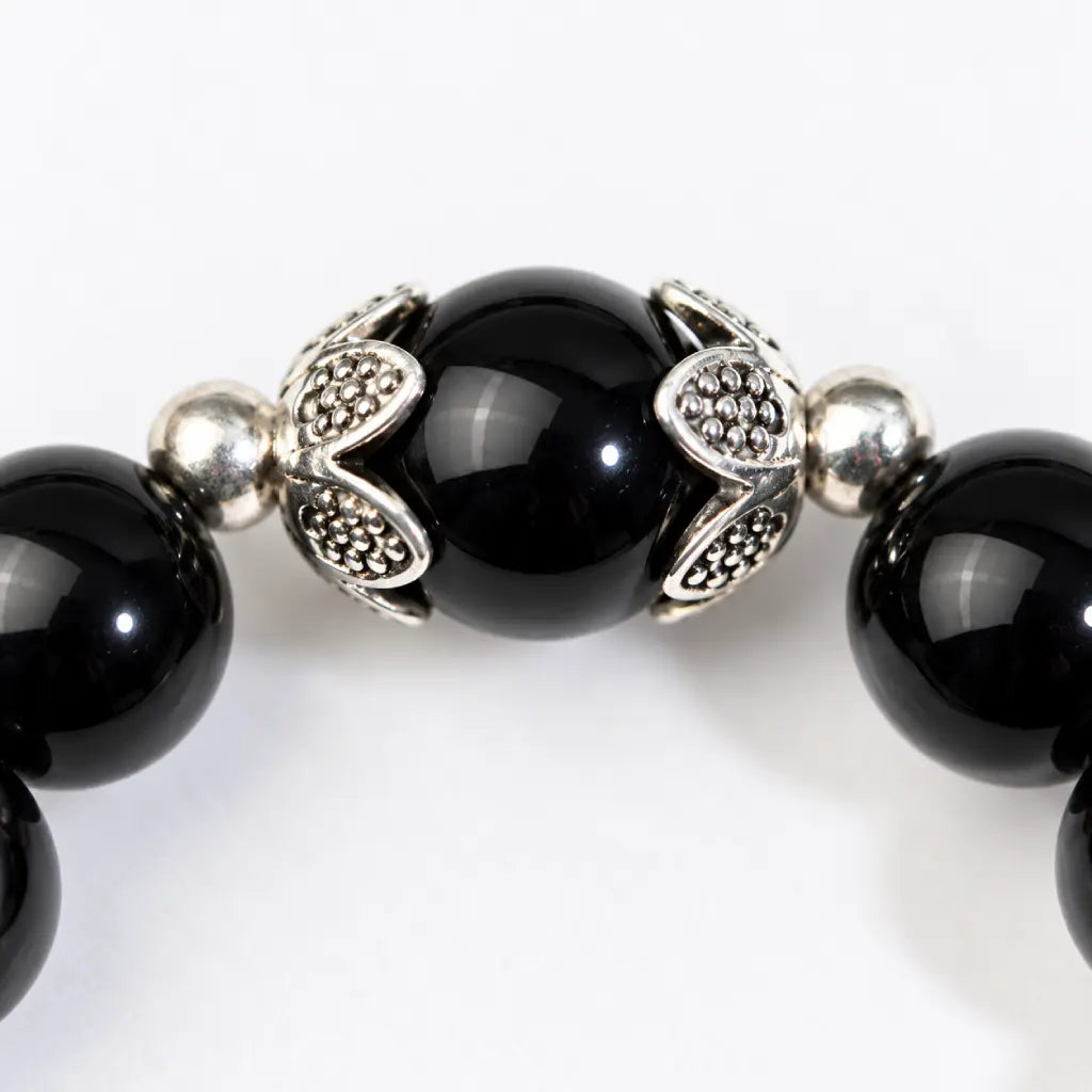 Shadow guardian obsidian bracelet close-up featuring a polished black bead with ornate silver accents for distinctive detailing.