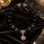 Shadow guardian obsidian bracelet featuring glossy black beads and silver charm, styled on velvet for a dramatic jewelry look.