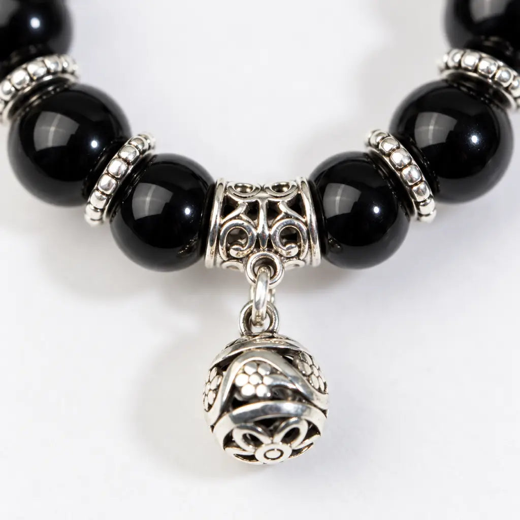 Shadow guardian obsidian bracelet close-up highlighting black beads and an ornate silver dangling charm for a statement finish.