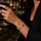 Person holding a glass of red wine with a colorful bracelet on a bar setting