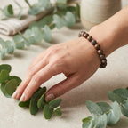 Snowflake bracelet premium brown stone beads beside eucalyptus leaves, nature-inspired crystal jewelry for calm gifting