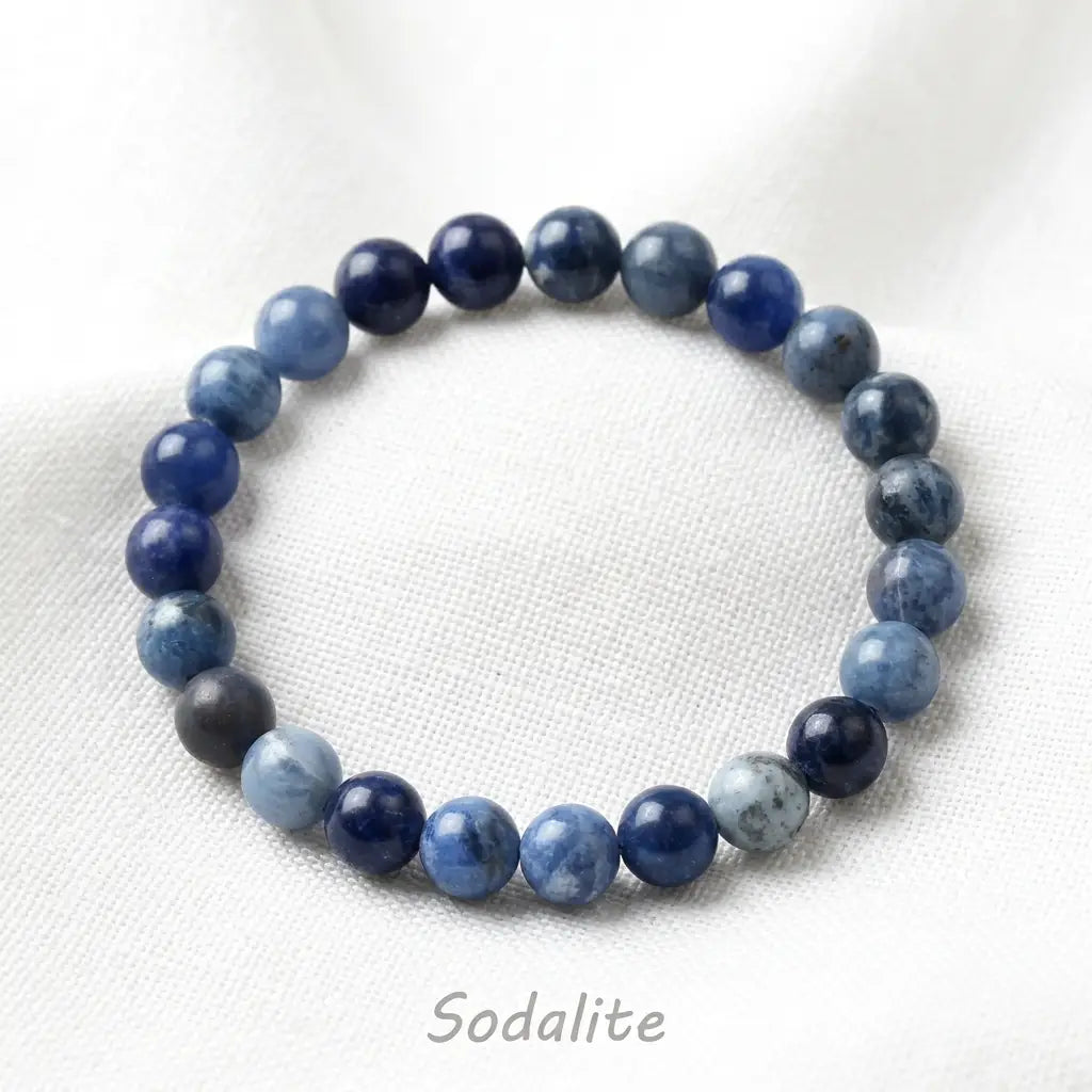 Sodalite stone bracelet blue round bead stretch bracelet on white fabric, calming crystal jewelry for mindful style