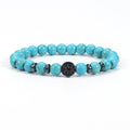 Synthetic turquoise bracelet with bright blue 8mm round beads, dark spacer rings, and a round black tree-design focal bead, shown in a clean front view on a plain white background.