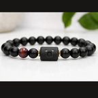 Taurus Zodiac Bracelet on white surface with black beads and tiger eye stone, modern astrology jewelry for balance calm energy and minimalist style