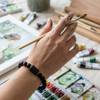Taurus Zodiac Bracelet worn by artist painting with black beads and tiger eye, creative astrology jewelry inspiring focus balance and energy