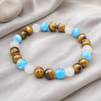 Tiger eye bracelet with blue and white gemstone beads displayed on soft fabric for elegant styling