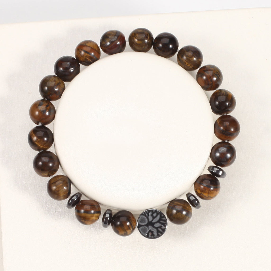 Tiger eye bracelet with glossy brown gold 8mm round beads, four dark spacer rings, and a round tree-design focal bead, seen from above on a white jewelry display form in full view.