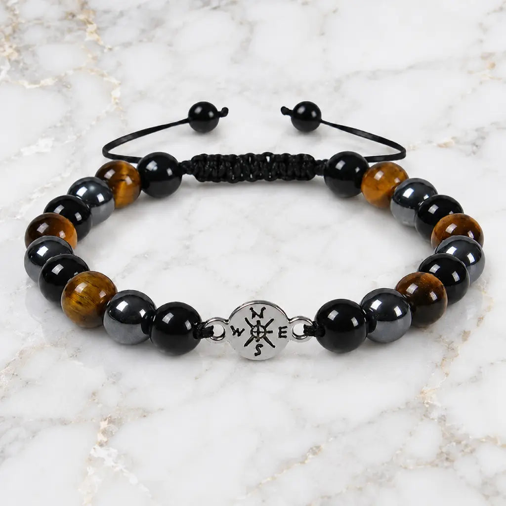 Tigereye bracelet with polished tiger eye and black gemstone beads on marble background for grounding style