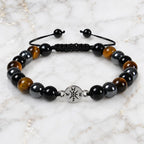 Tigereye bracelet with polished tiger eye and black gemstone beads on marble background for grounding style
