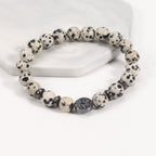 Tree of life stone bracelet in the Spotted Stone option, with cream and black-spotted 8mm beads, black spacer rings, and a round dark tree-design focal bead in bright studio light.