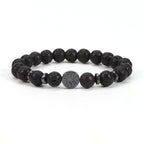 Tree of life stone bracelet in the Volcanic Rock option, with porous black 8mm round beads, black spacer rings, and a round dark tree-design focal bead on a clean white background.
