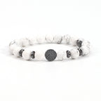 Tree of life stone bracelet in the White Turquoise option, showing white and gray-veined 8mm beads, black spacer rings, and a round dark tree-design focal bead on a white backdrop.