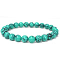 Turquoise howlite bracelet with polished 8mm round beads, dark natural style veining and a plain stretch design, photographed in a circular arrangement on a clean white background.