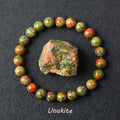Unakite bracelet with green and pink beads beside a natural raw Unakite stone
