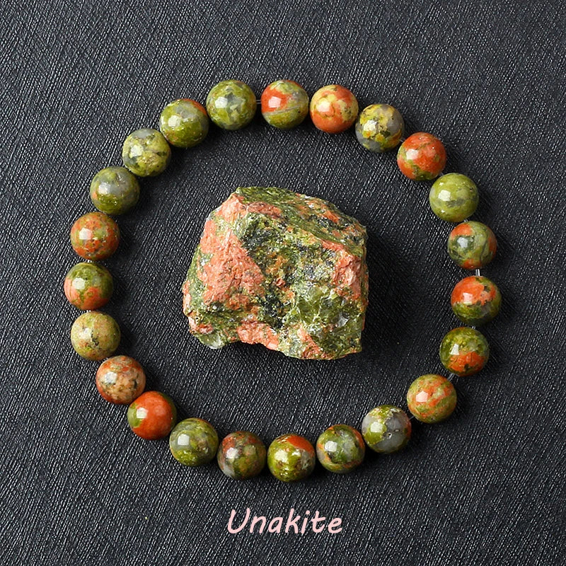 Unakite bracelet with green and pink beads beside a natural raw Unakite stone