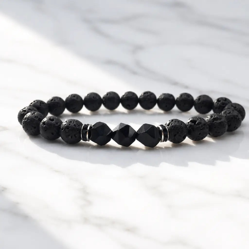 Volcanic stone bracelet on white marble with textured lava beads and black crystal accents for sleek modern style