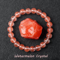 Watermelon Crystal bracelet with coral pink translucent beads surrounding a raw red-orange crystal specimen on dark background