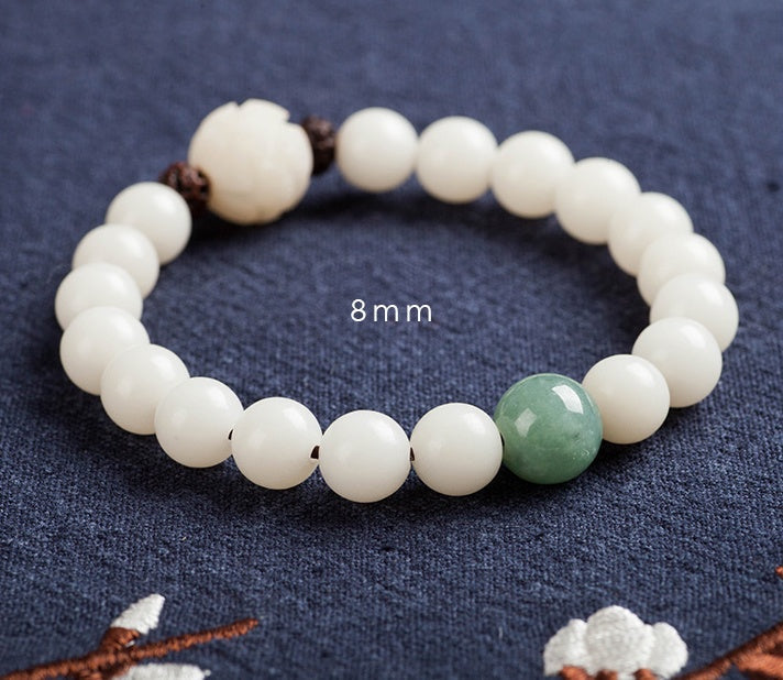 White bodhi seed bracelet close-up marked 8 mm, showing smooth ivory-color beads, one green accent bead, two dark spacers, and a carved white lotus-style focal bead in fuller view.