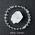 White Crystal bracelet with clear polished quartz beads surrounding a raw white quartz specimen on dark background