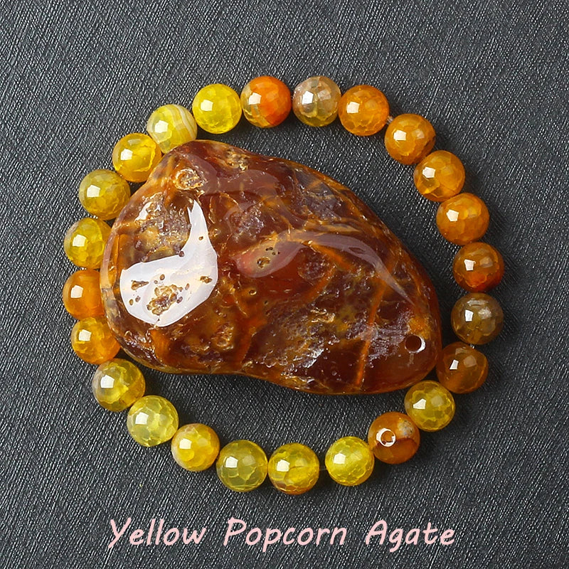 Yellow Popcorn Agate stone surrounded by yellow and orange beads on a dark fabric background