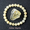 Yellow Quartz bracelet with soft pale cream beads surrounding a raw golden quartz specimen on dark background