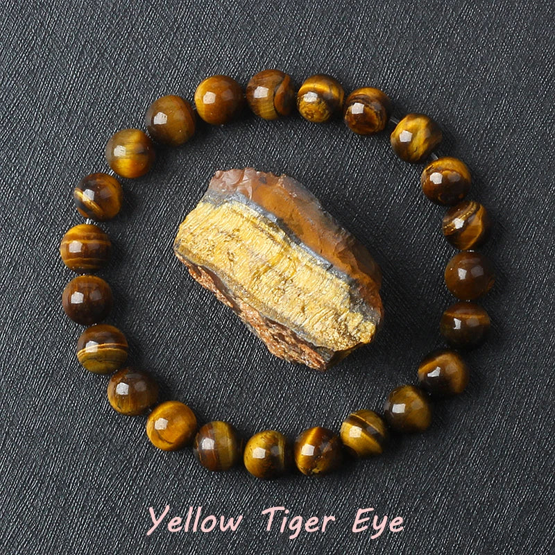 Yellow Tiger Eye bracelet with golden brown chatoyant beads surrounding a raw tiger eye specimen on dark background