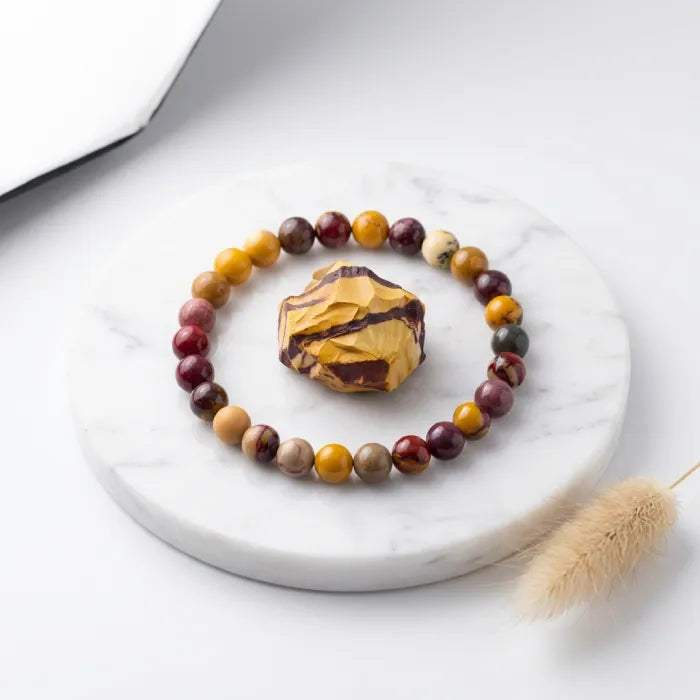 Yolk Stone Bracelet displayed with raw mookaite on marble base, premium crystal jewelry enhancing balance and calm energy