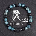 Zodiac bracelet, Aquarius option, with blue-green jasper, matte black onyx, hematite spacers, and a black Aquarius centerpiece, shown in a focused full product view on dark fabric.